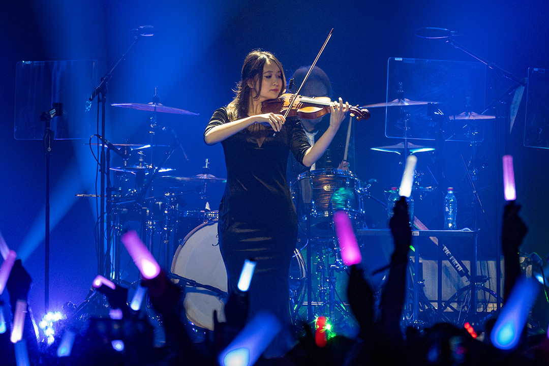 A member of the Final Fantasy 14 Community team playing the violin on stage with the Primals at Fan Festival 2026 in Berlin.