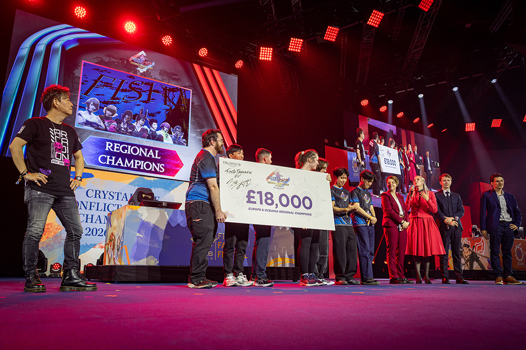 Final Fantasy 14 Producer and Director Naoki Yoshida standing onstage watching as the winning team of the Crystalline Conflict Regional Championship 2026 Europe and Oceania receive their cheque, with the hosts and commentators next to them.