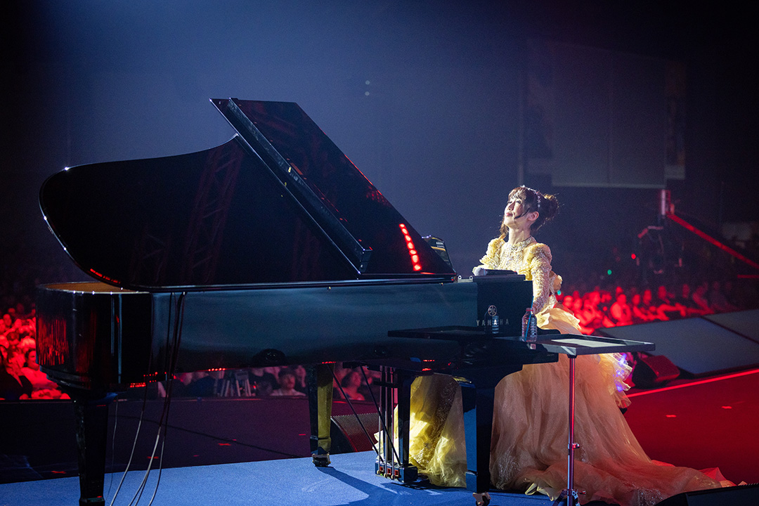 Pianist Keiko, wearing a voluminous golden ballgown, performs at the piano concert at Fan Festival 2026 in Berlin.